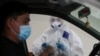 Kazakhstan - A health worker approaches a car driver at a mobile testing station for the coronavirus disease (COVID-19) in Almaty, Kazakhstan June 17, 2020. REUTERS/Pavel Mikheyev