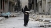 Syria -- A woman carries bread through a damaged street in Aleppo, January 30, 2017