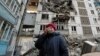 A local resident reacts next to the building where her destroyed apartment is located in the besieged city of Mariupol